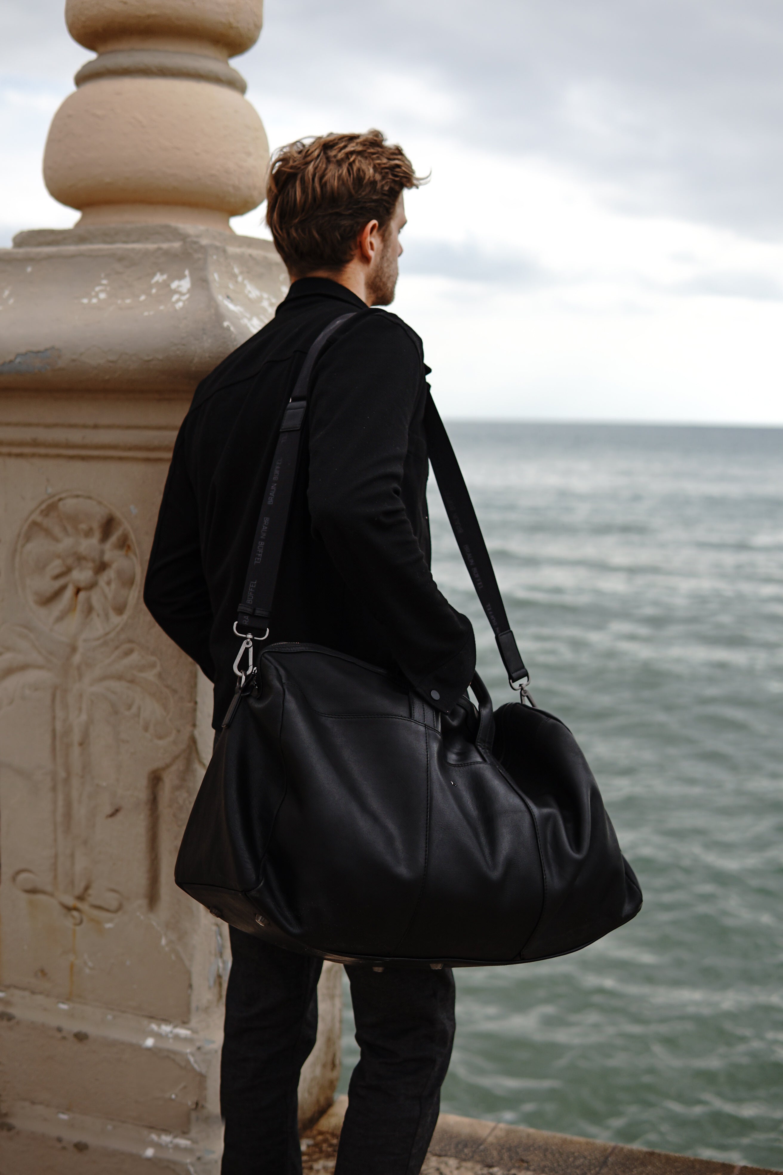Mann trägt schwarze Ledertasche
