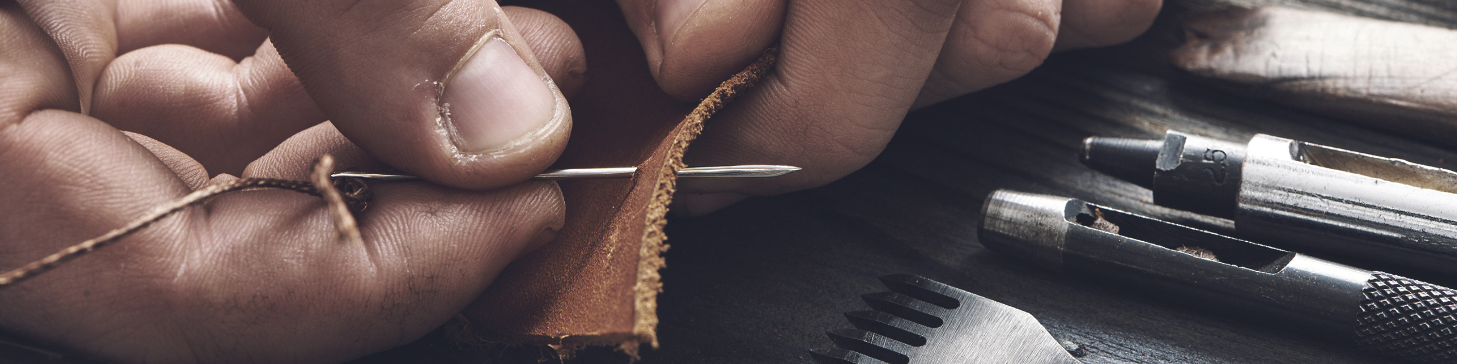 Mann näht das Leder