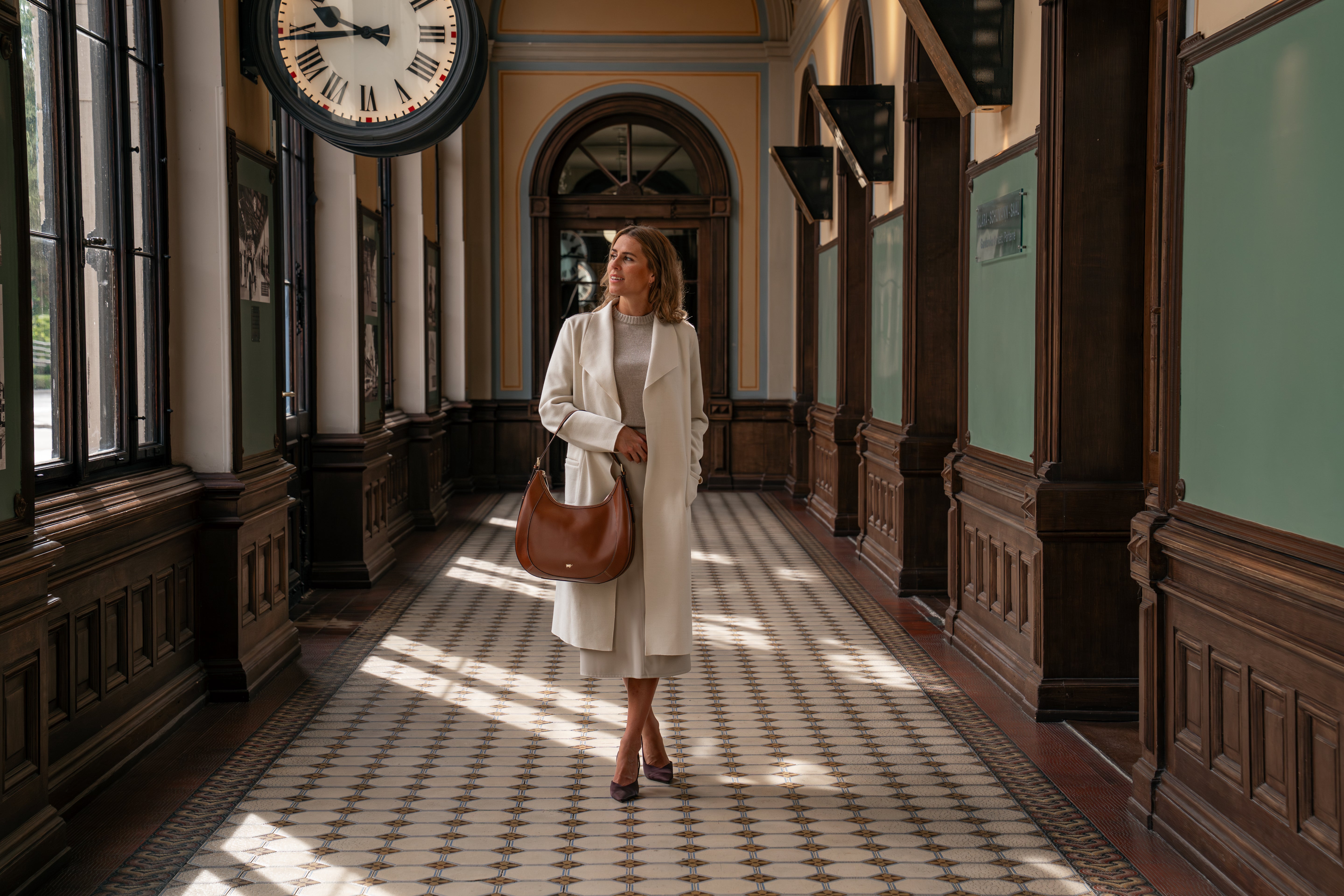 Frau im weißen Mantel mit brauner hochwertiger Ledertasche