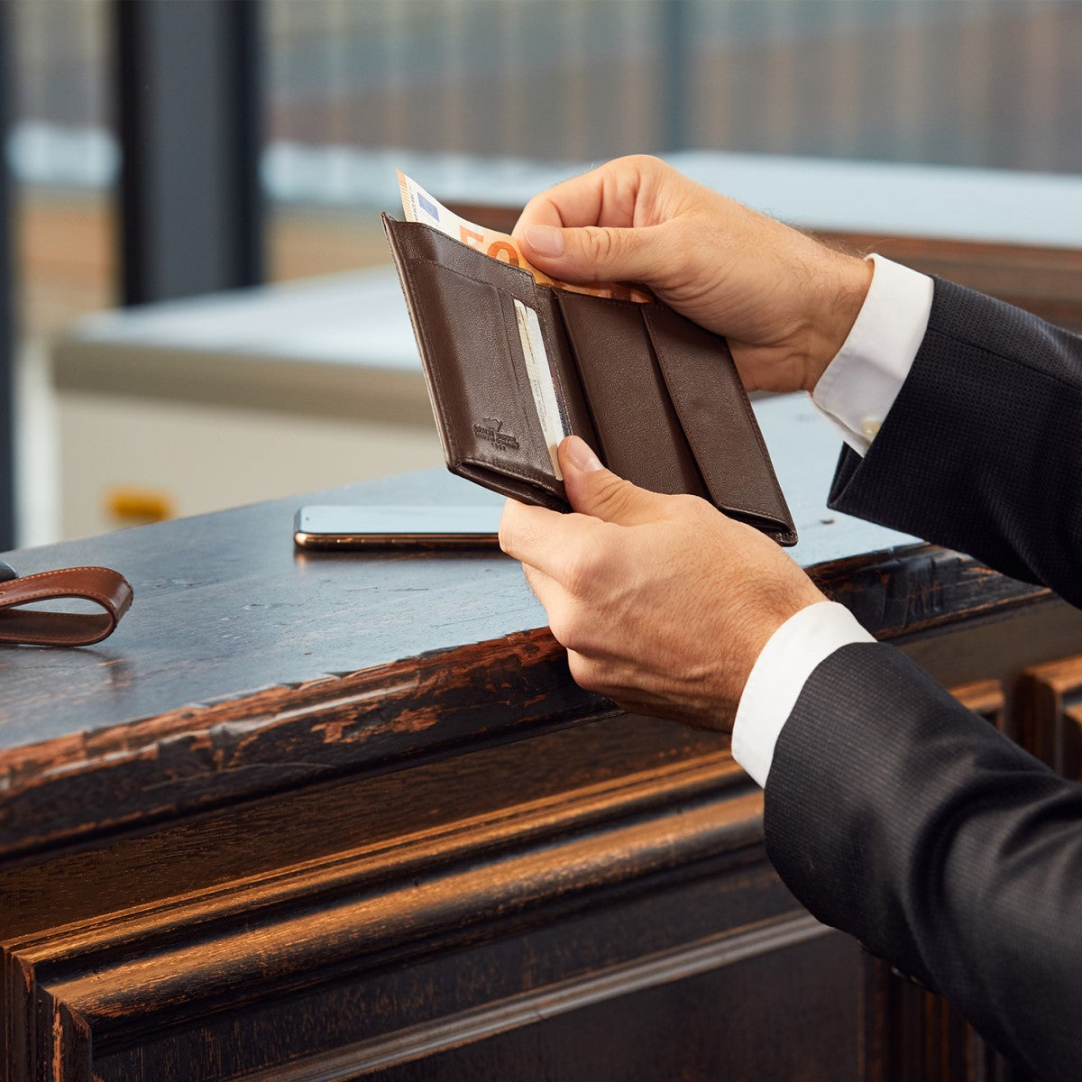 Cordovan Pferdeledergeldbörse in der Hand eines Mannes mit Anzug