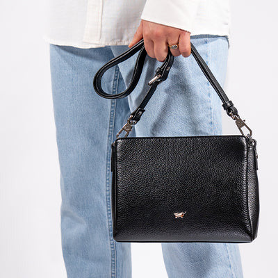 Frau trägt eine schwarze Handtasche vor Ihrem linken Bein