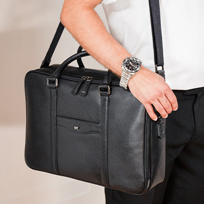 Mann trägt eine schwarze Business-Ledertasche auf seine rechten Seite