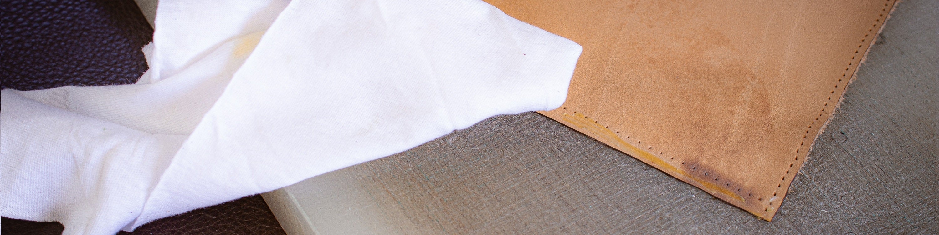 Leder mit einem Fettfleck drauf und ein Tuch daneben