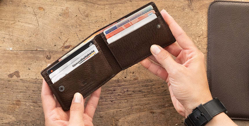 Mann hält eine braune Ledergeldbörse in der Hand