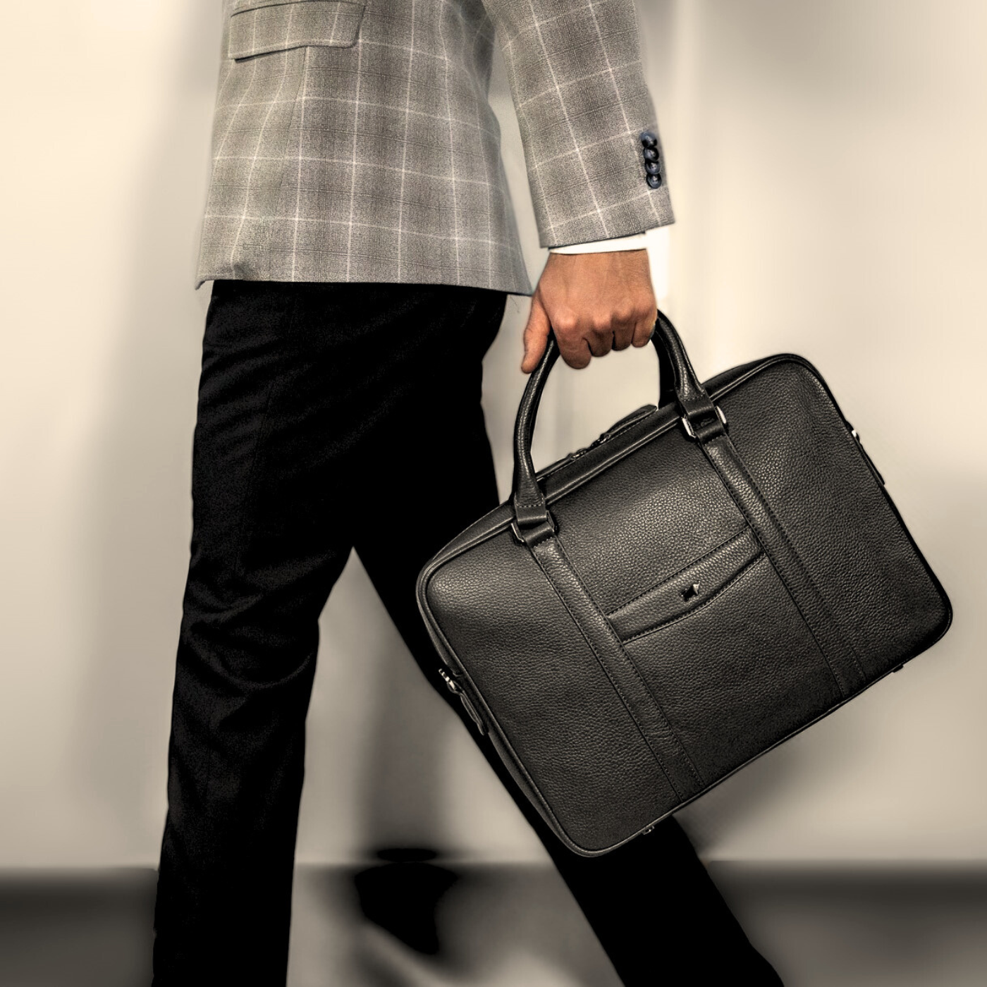 Mann im kariertem Sakko mit schicker Businesstasche aus Leder