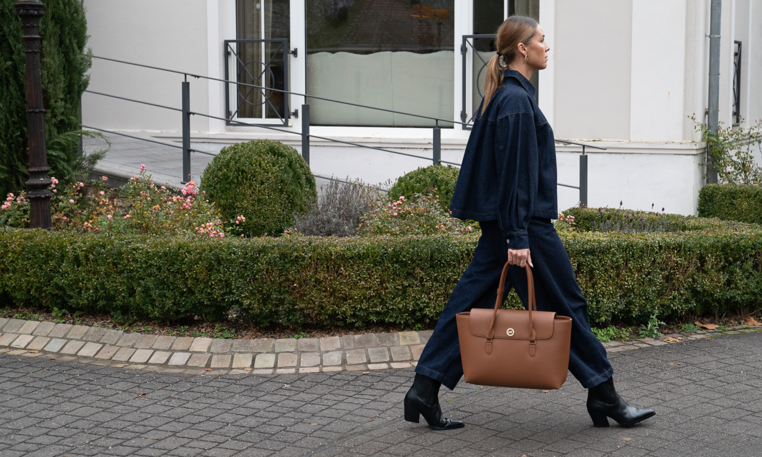 Frau geht mit einer trendigen Ledertasche in der Hand